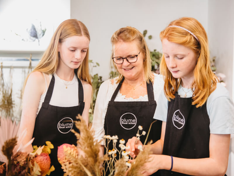 Mother and daughters looking at a dried flower arrangement