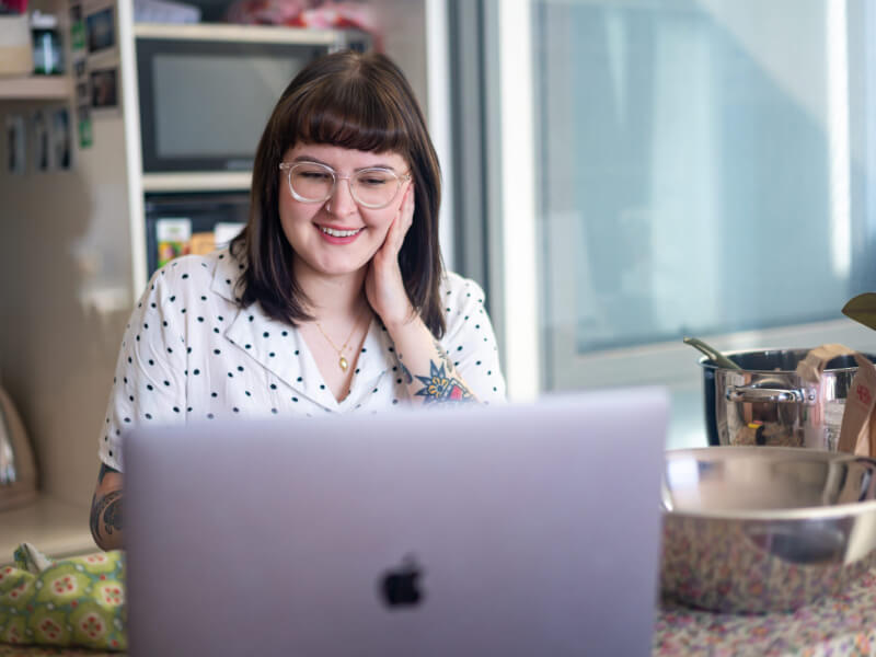 Woman behind computer smiling at her screen