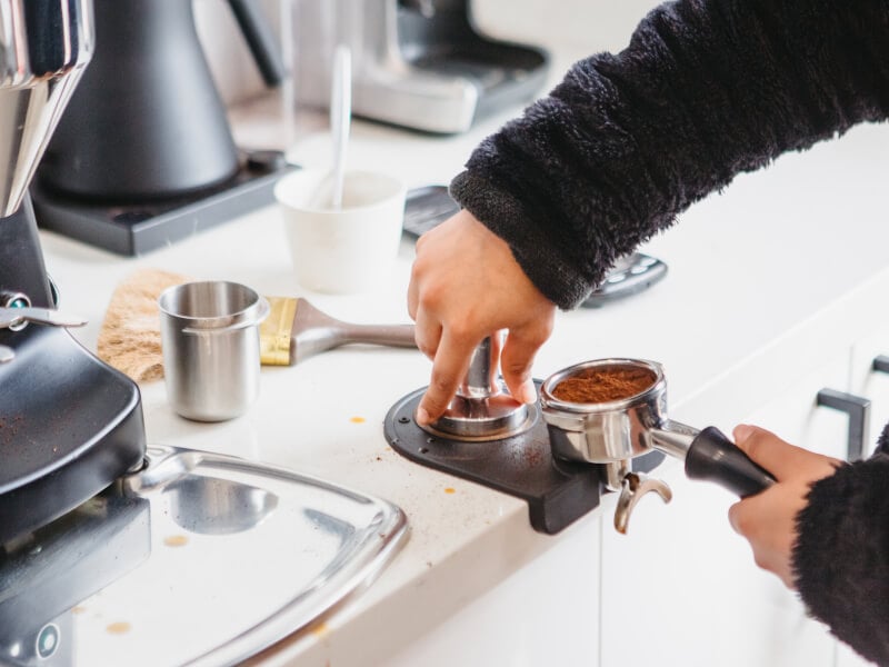 Person in the process of tamping coffee