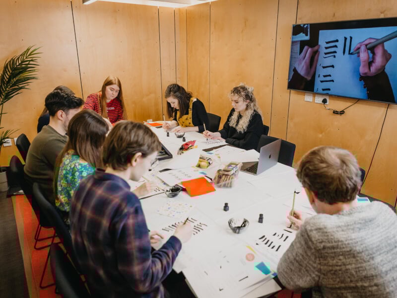 A group of people learning calligraphy over Zoom.