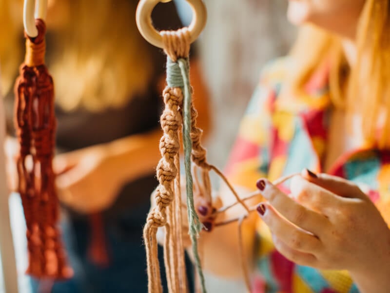 A woman's hands work on a macrame pot hanger
