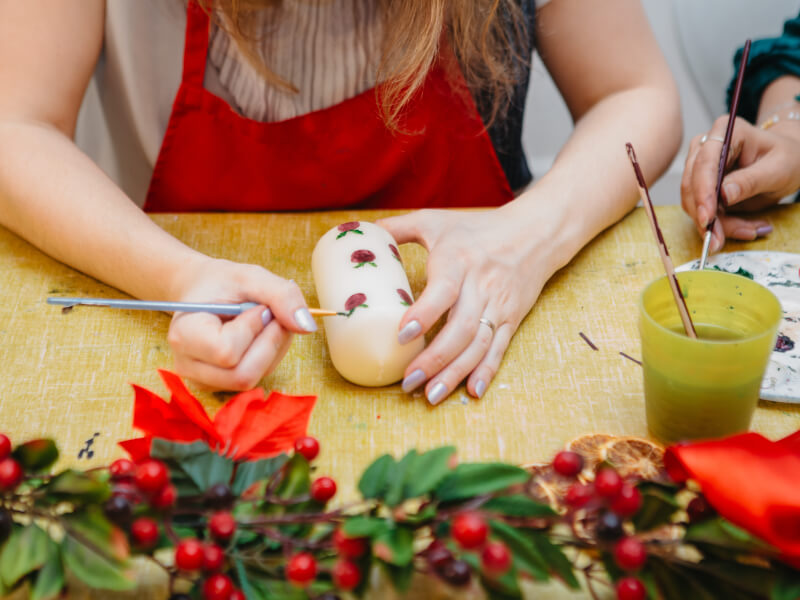 Woman painting her own candle with a Christmas design