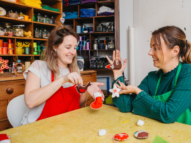 Women holding their DIY Christmas ornaments