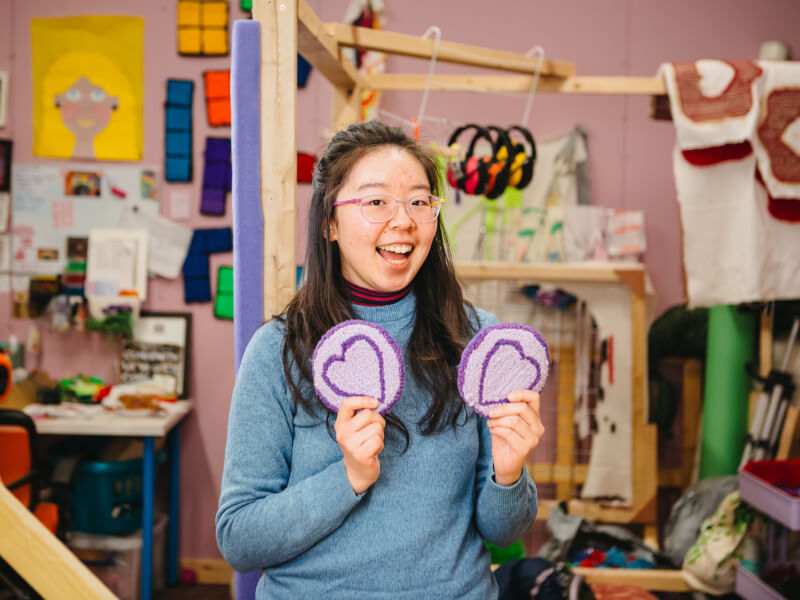 Woman smiling and holding up tufted coasters