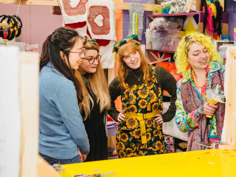 Group of women watching teacher tuft a rug