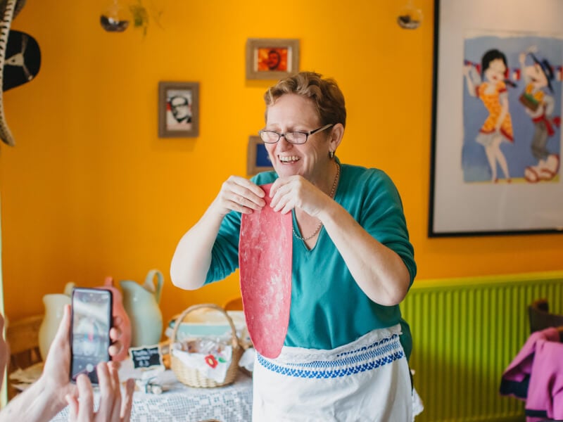 Person taking a photo of woman holding handmade pasta dough