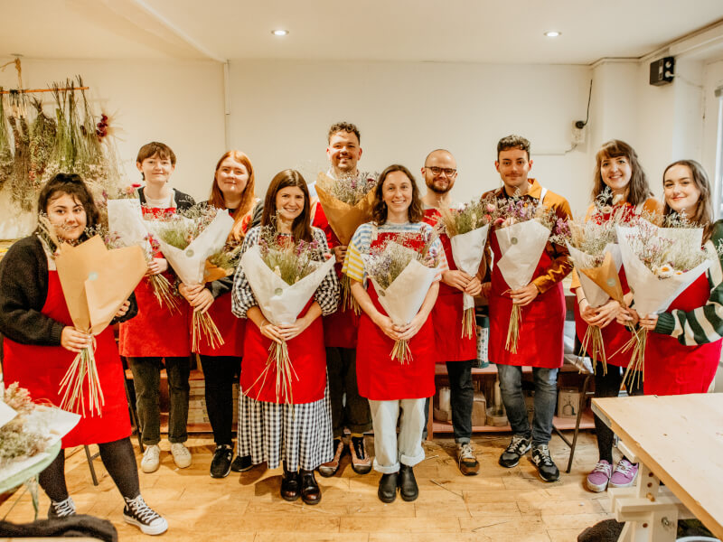 Team holding their flower arrangements side by side