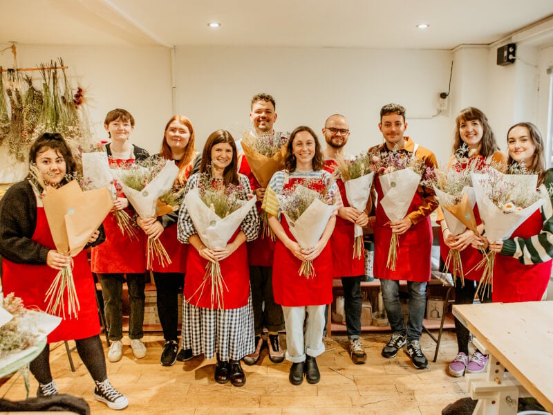 A group of colleagues holding their dried flower arrangements