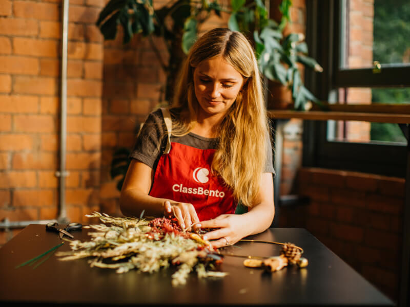Woman wearing apron making DIY Christmas wreaths. 