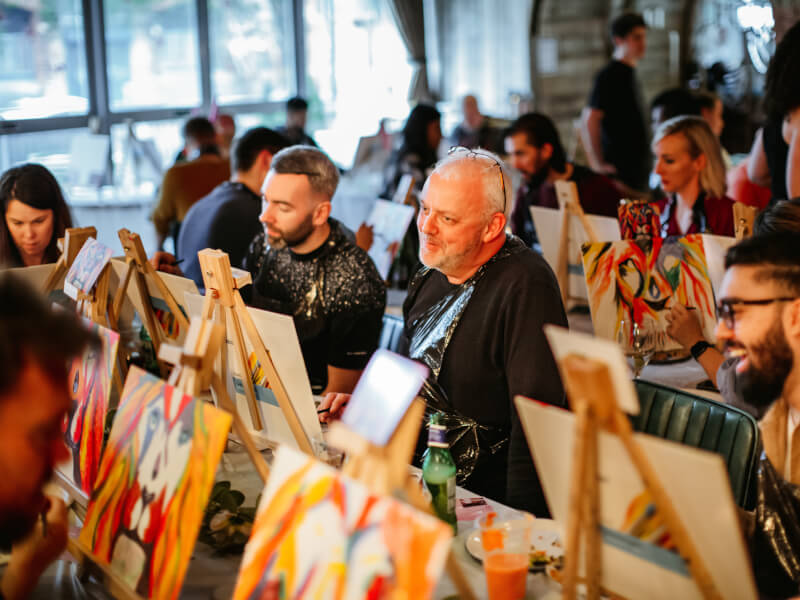 People smiling at a paint and sip class. 