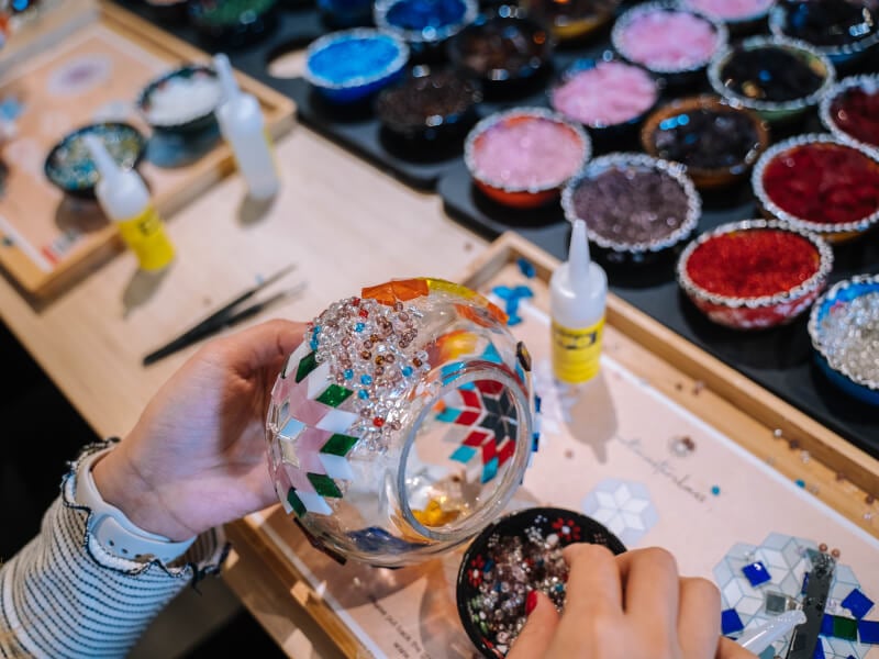 Close-up of woman putting mosaic tiles and beads on lamp