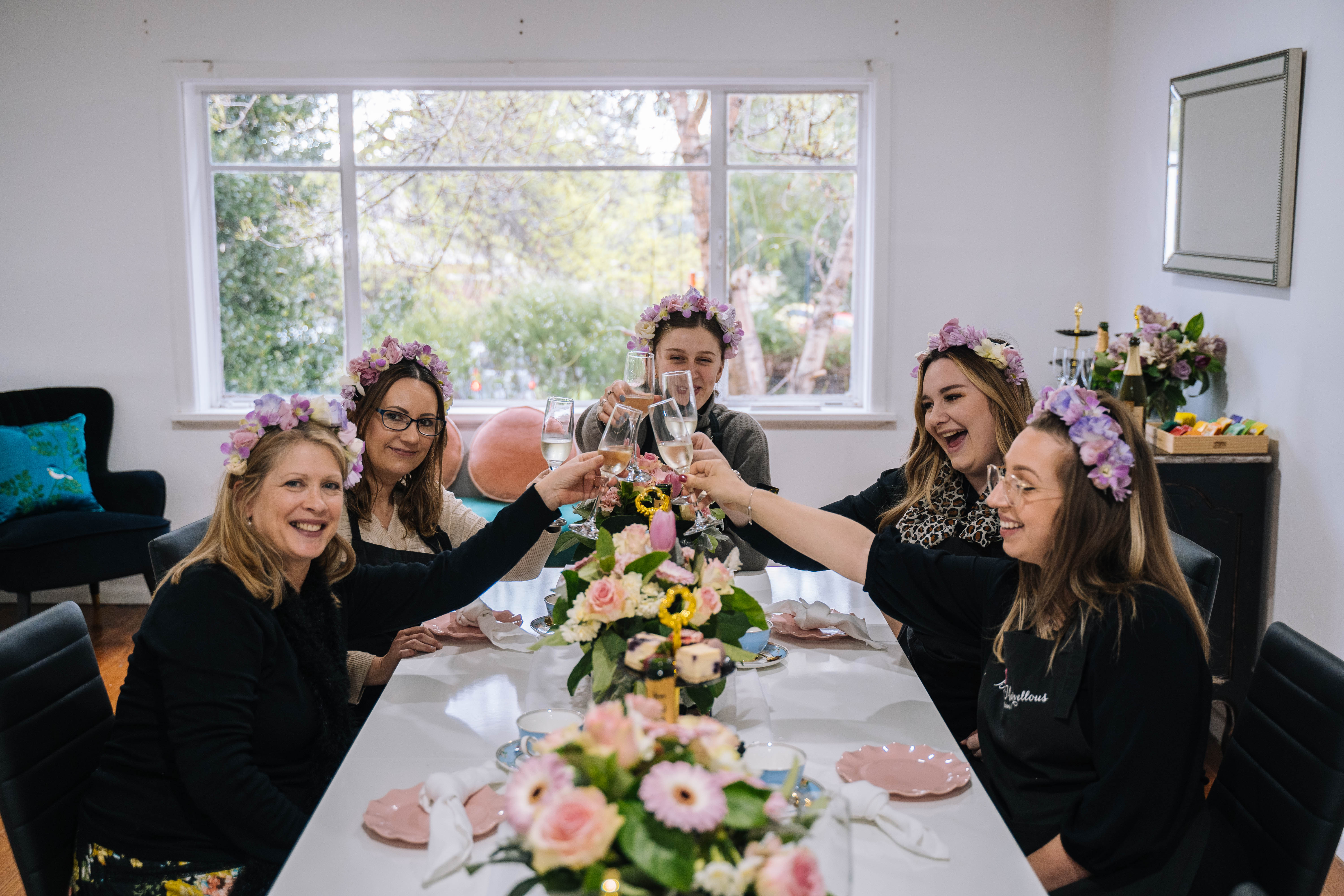 Group of women clinking their glasses and wearing dried flower crowns