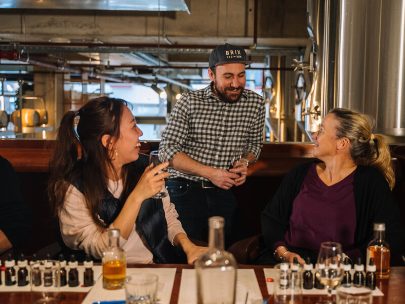 A bartender chats to some cocktail making students