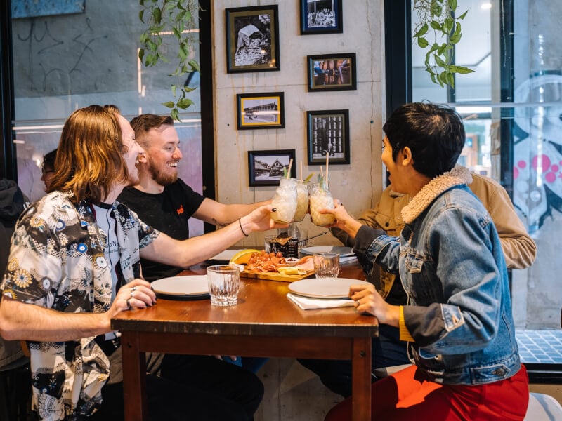 People clinking cocktail jars