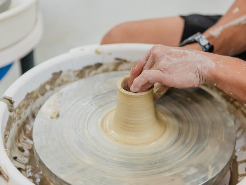 Hands sculpting clay on a pottery wheel