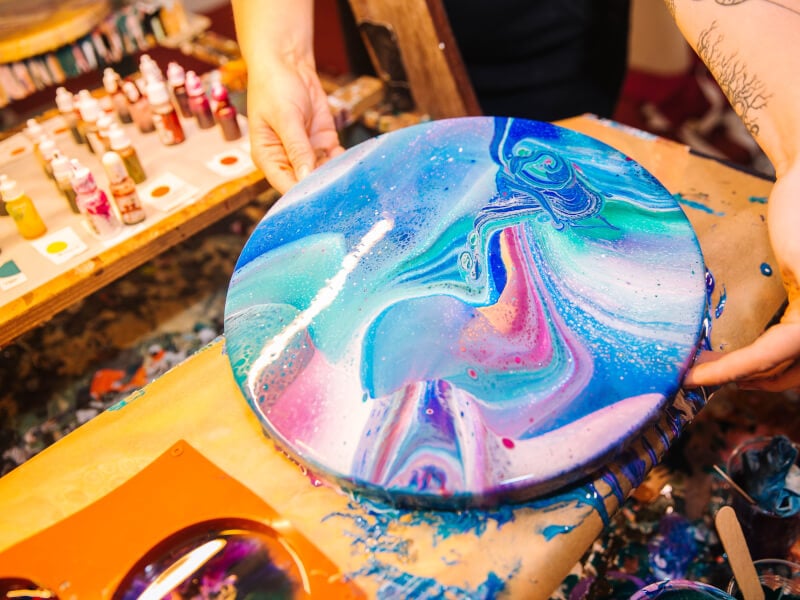 Chelsey holding up paint pouring artwork