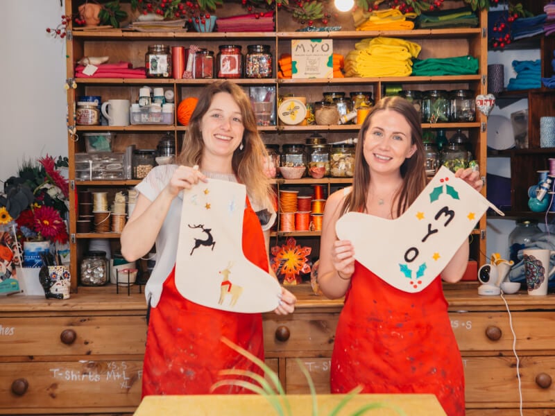 Two friends pose with their handmade Christmas stockings
