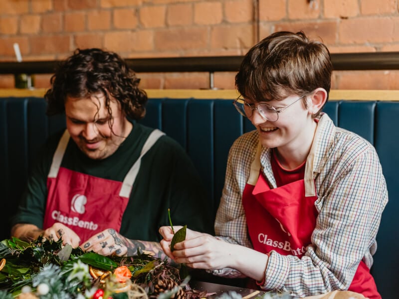 Two people making a Christmas wreath