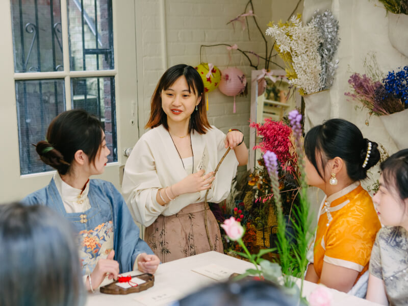 Women dressed in traditional Asian garments with flowers in the background