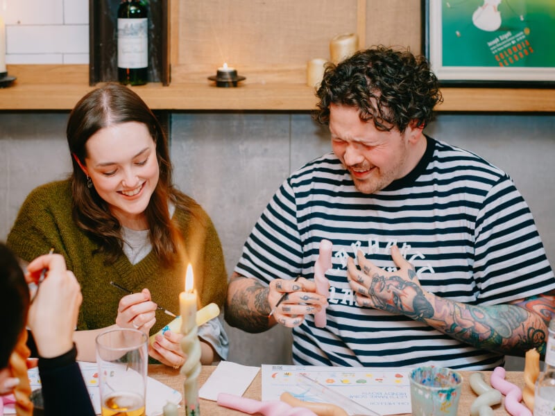 Two people laughing at a candle painting class