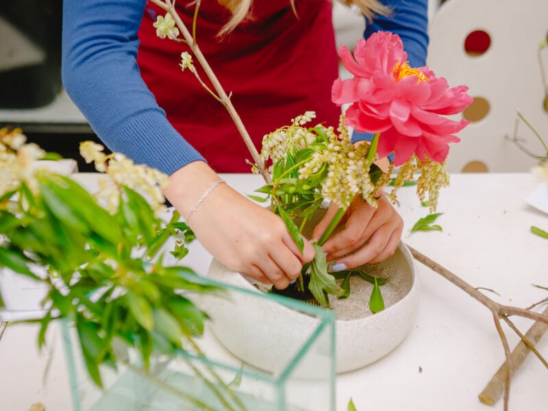Woman arranging an ikebana display in a ceramic bowl
