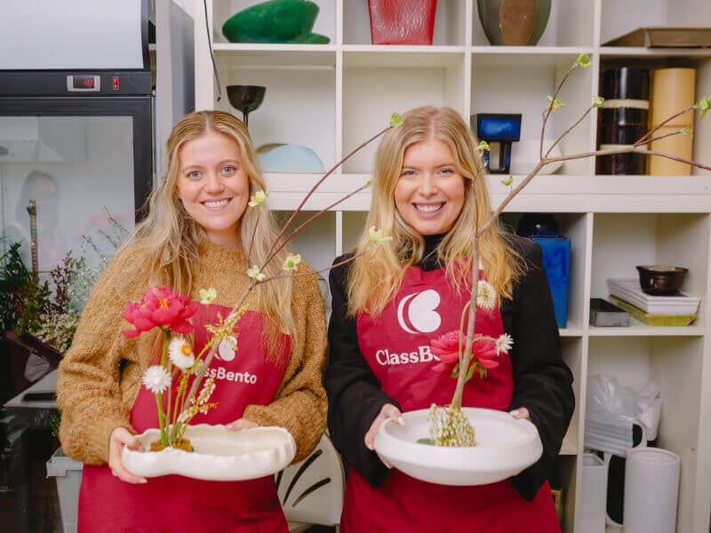 Two women smiling and holding their Ikebana arrangements