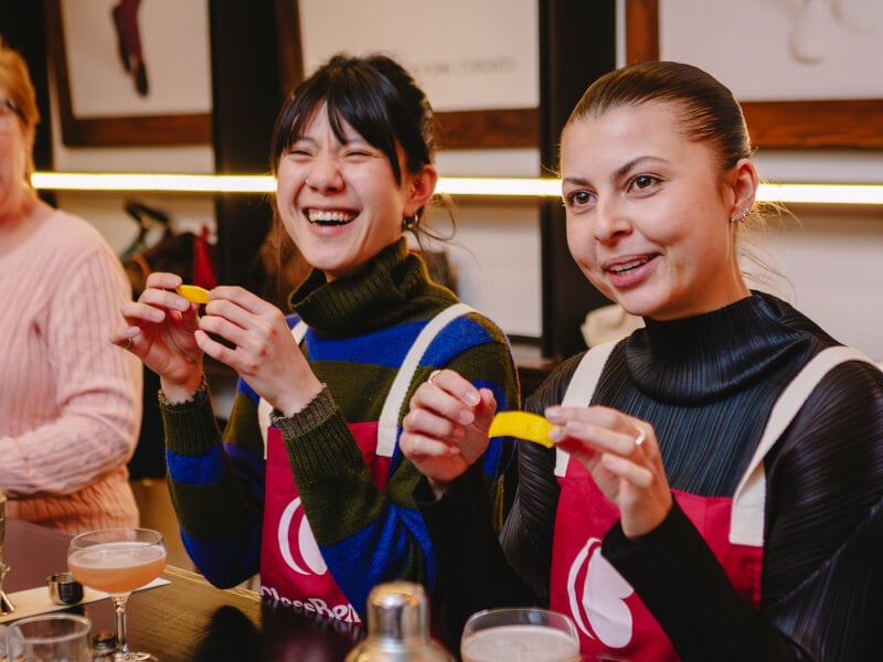 Women holding lemon peels at a cocktail making class
