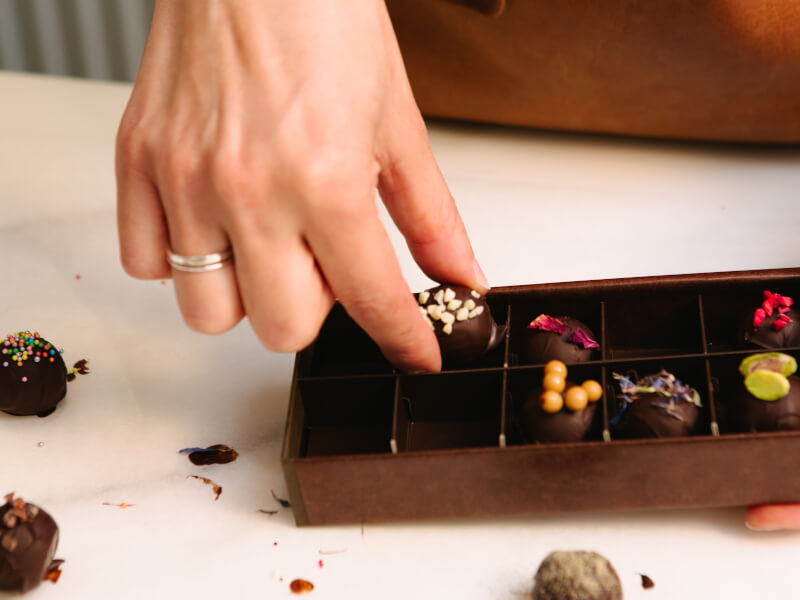 Hand reaching into a box of chocolate truffles