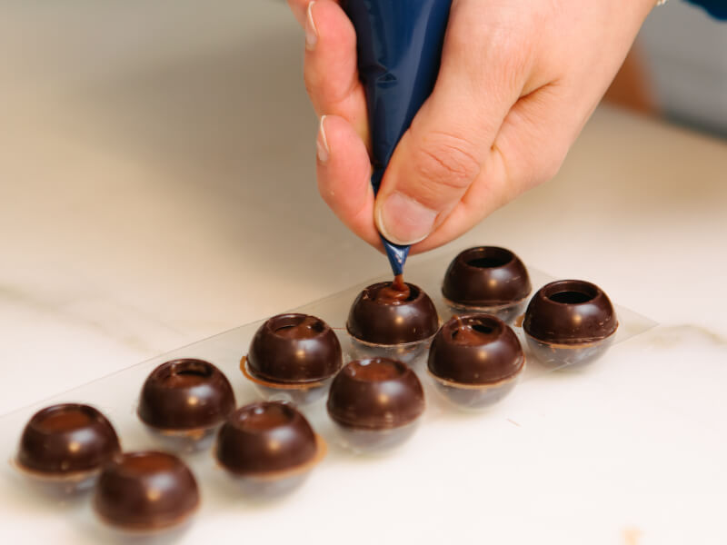 Hand piping ganache into chocolates
