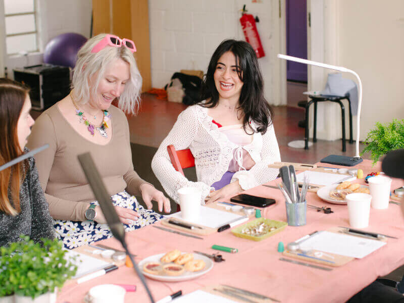 Women laughing together at a silversmithing class