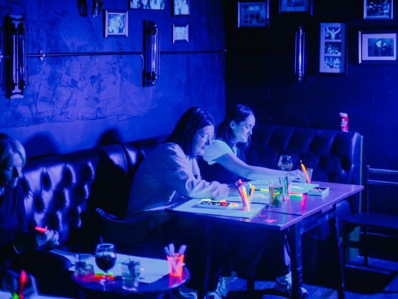 People drawing in a neon life drawing class