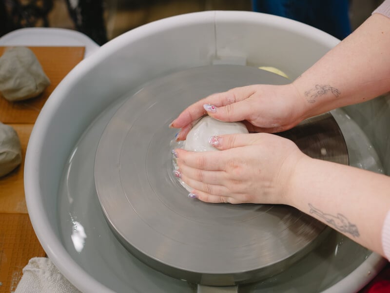 Person shaping clay on pottery wheel