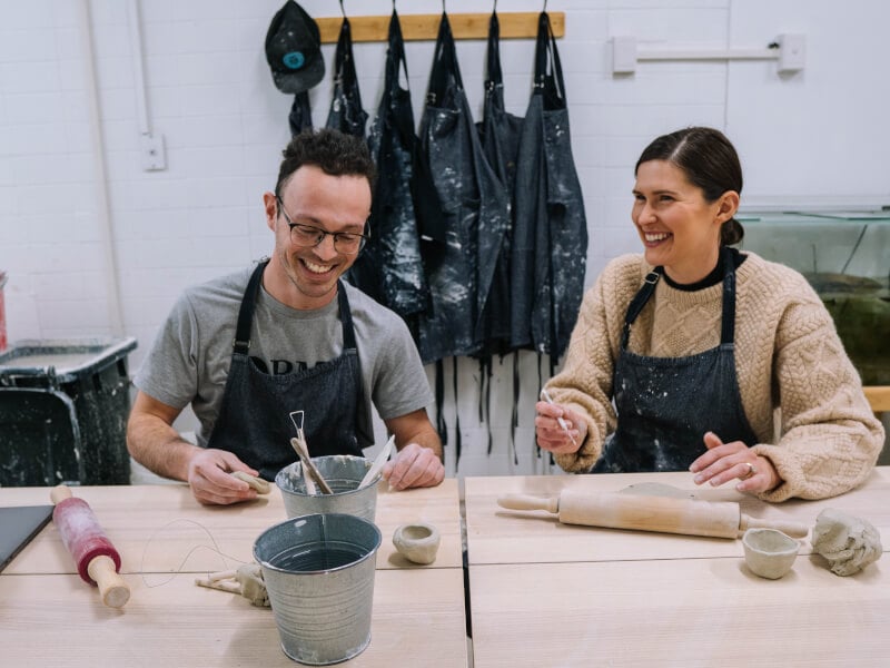 Two people hand building clay