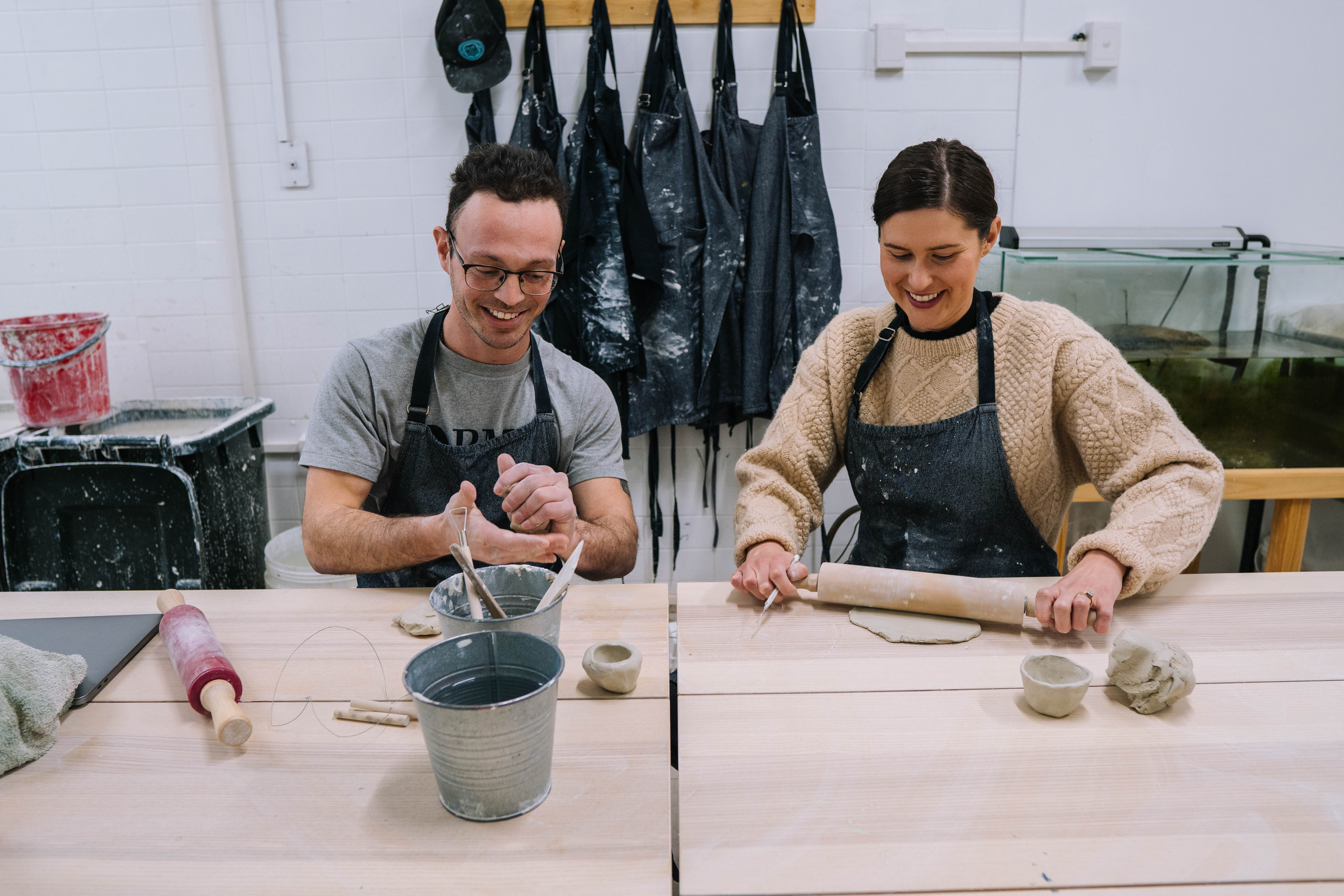 A man and a woman hand building clay
