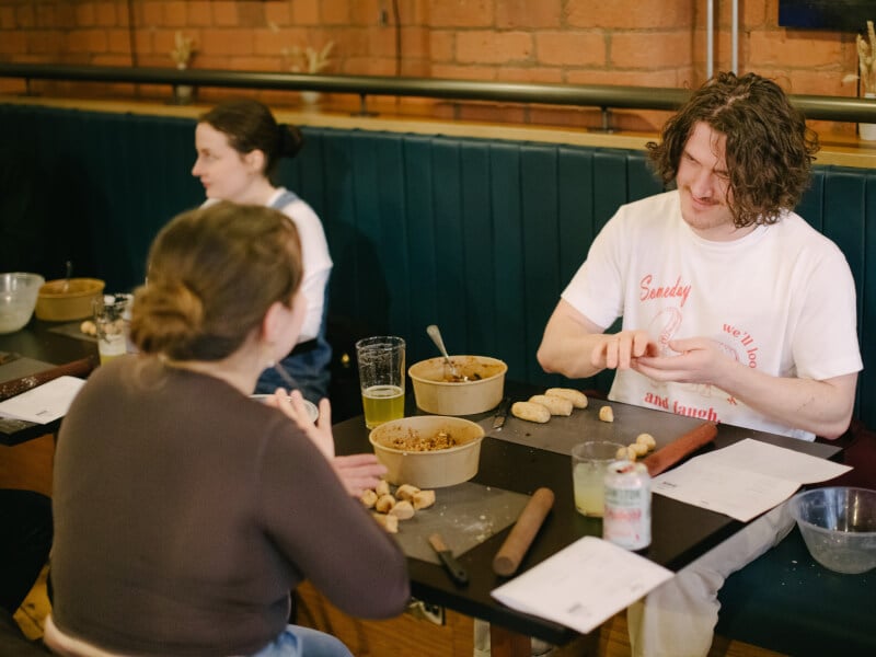 Couple sitting a restaurant table folding dumplings