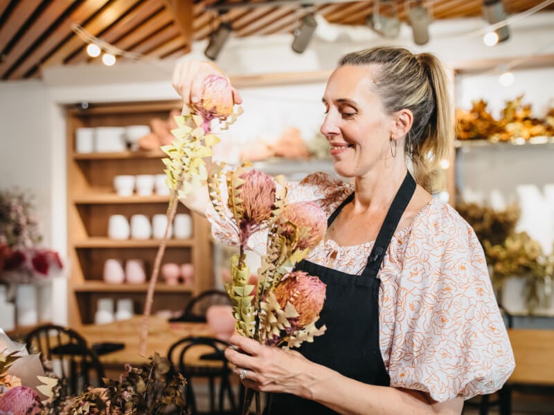 woman smiling with flower arrangement