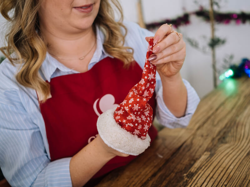 A woman wearing an apron holding DIY Christmas decorations.