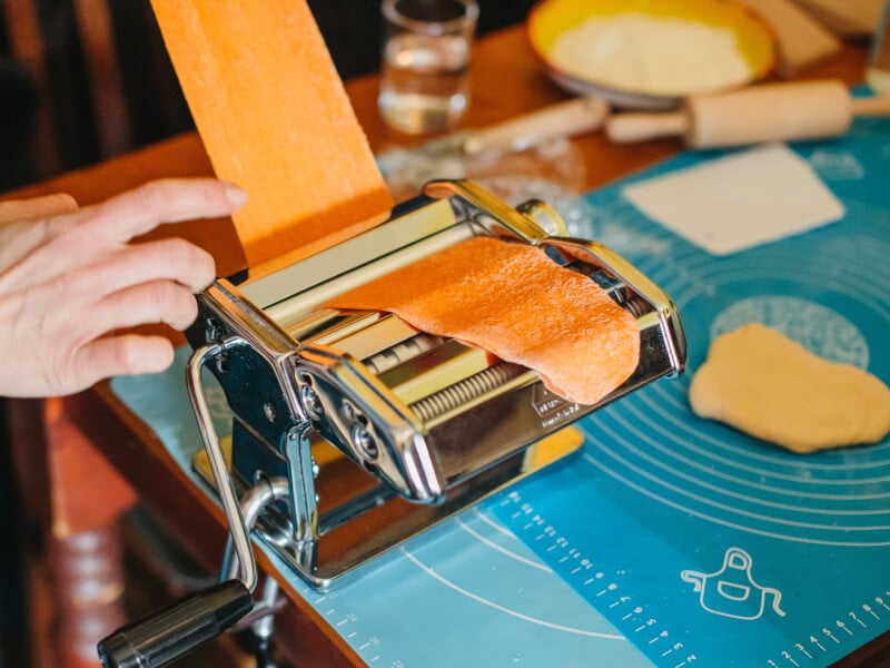 Fresh orange dough going through the pasta machine