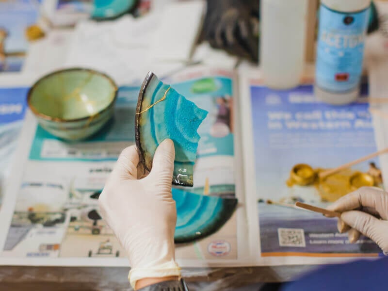 Gloved hand holding a piece of broken pottery