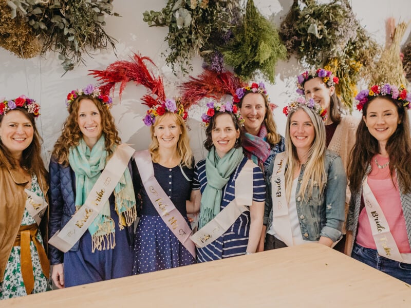 Group of bridesmaids and bride wearing sashes and flower crowns.jpg