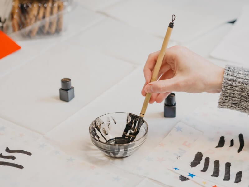 Hand holding a Japanese calligraphy brush doing a stroke 