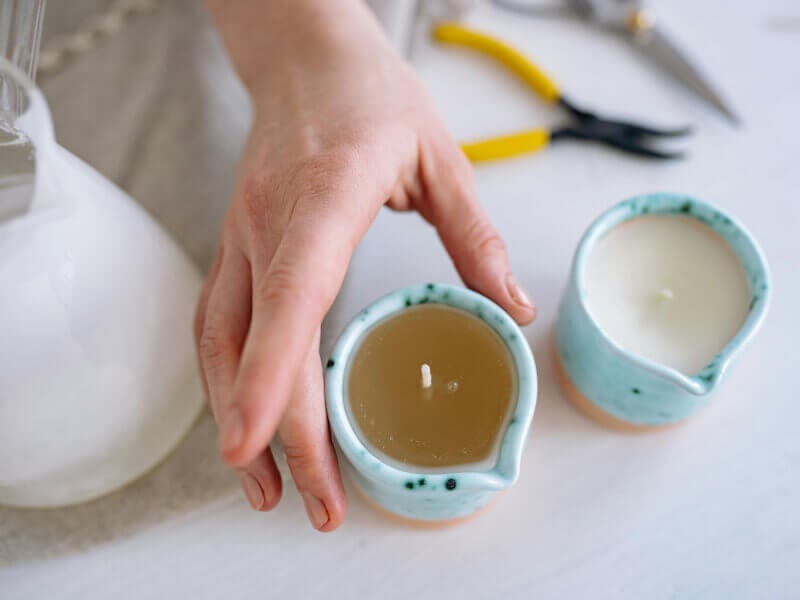 Hand reaching for one of two hand-poured candles