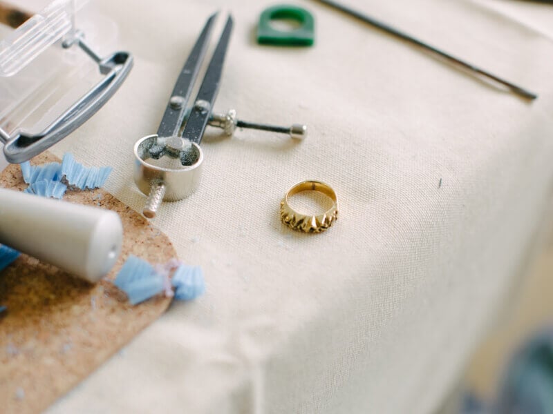 Handmade ring lying on table next to silversmithing tools