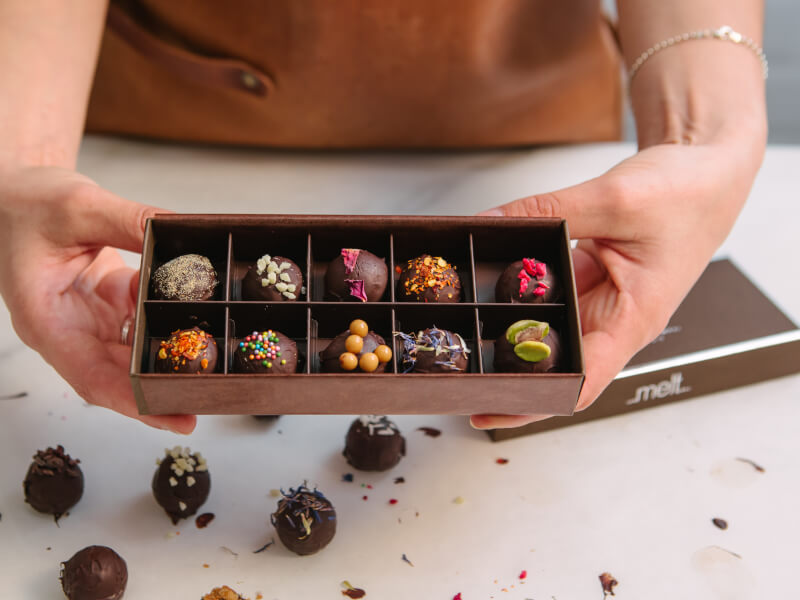 Close-up of hands holding a box of ten handmade chocolates