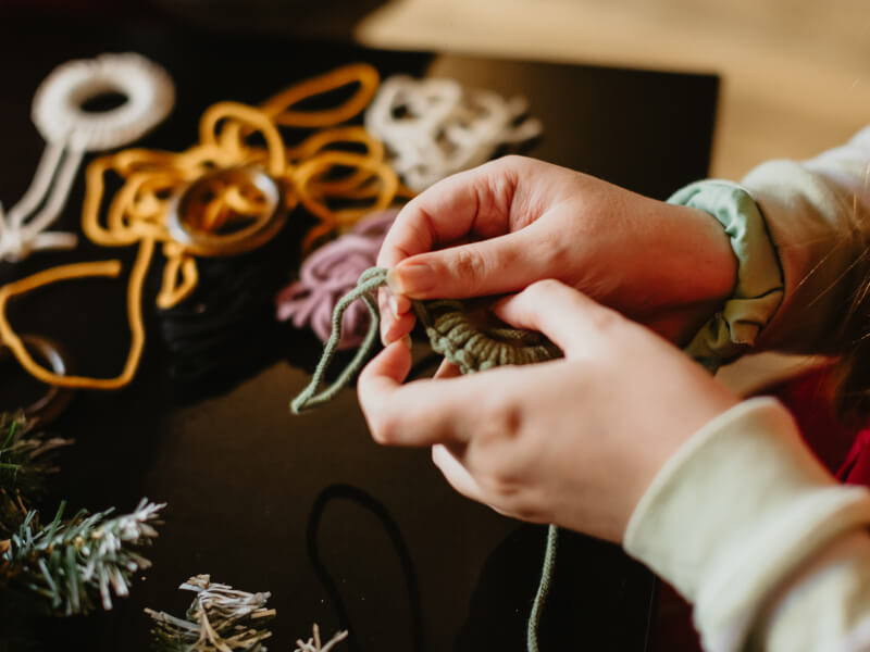 Hands holding green macrame Christmas decoration