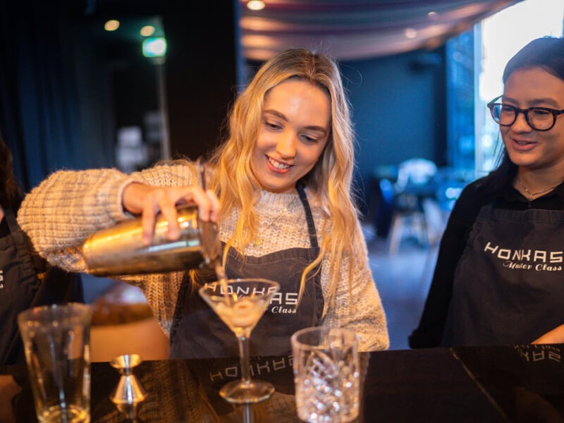 A woman and her colleague pours cocktails at their festive cocktail team building party