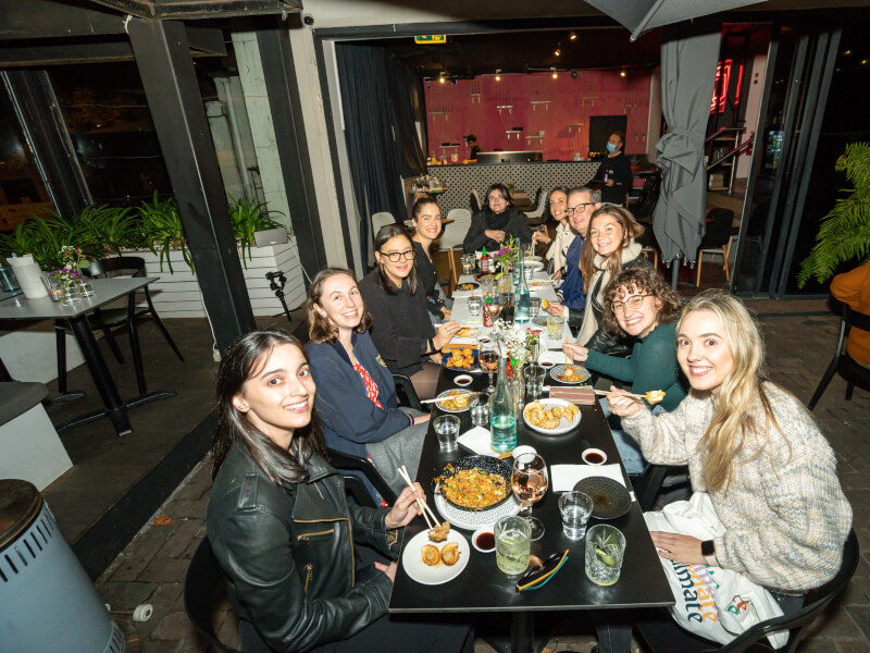 Colleagues sitting around a table with dumplings and cocktails