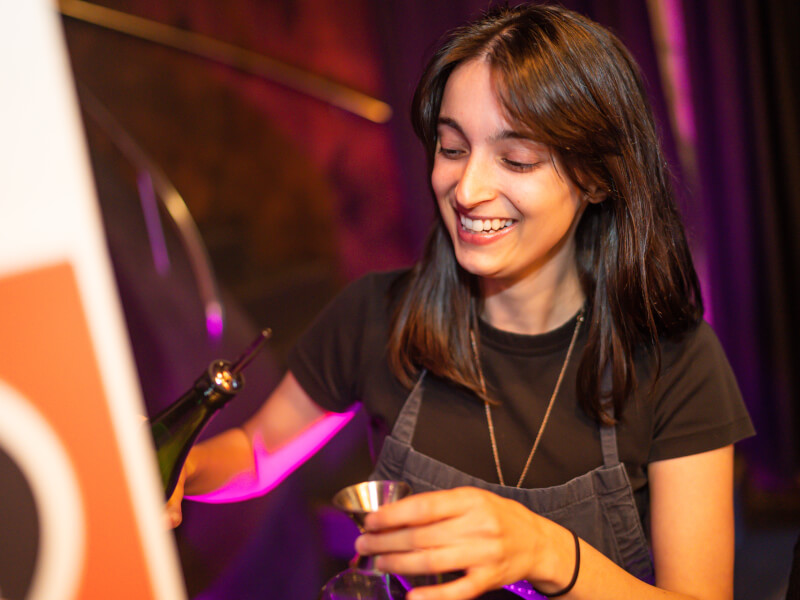 woman smiling and making cocktails