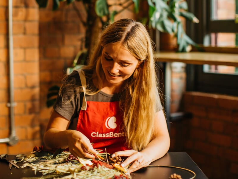 Woman wearing red apron making a DIY Christmas wreath