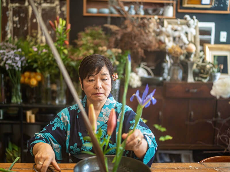 Japanese women in blue kimono arranging Ikebana display